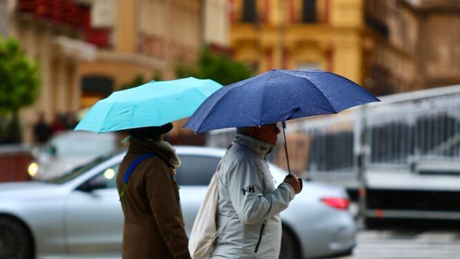 Dos personas se protegen de la lluvia en el centro de Málaga.